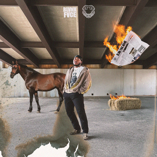 Man standing next to a horse with a burning newspaper and hay bale in an industrial setting.